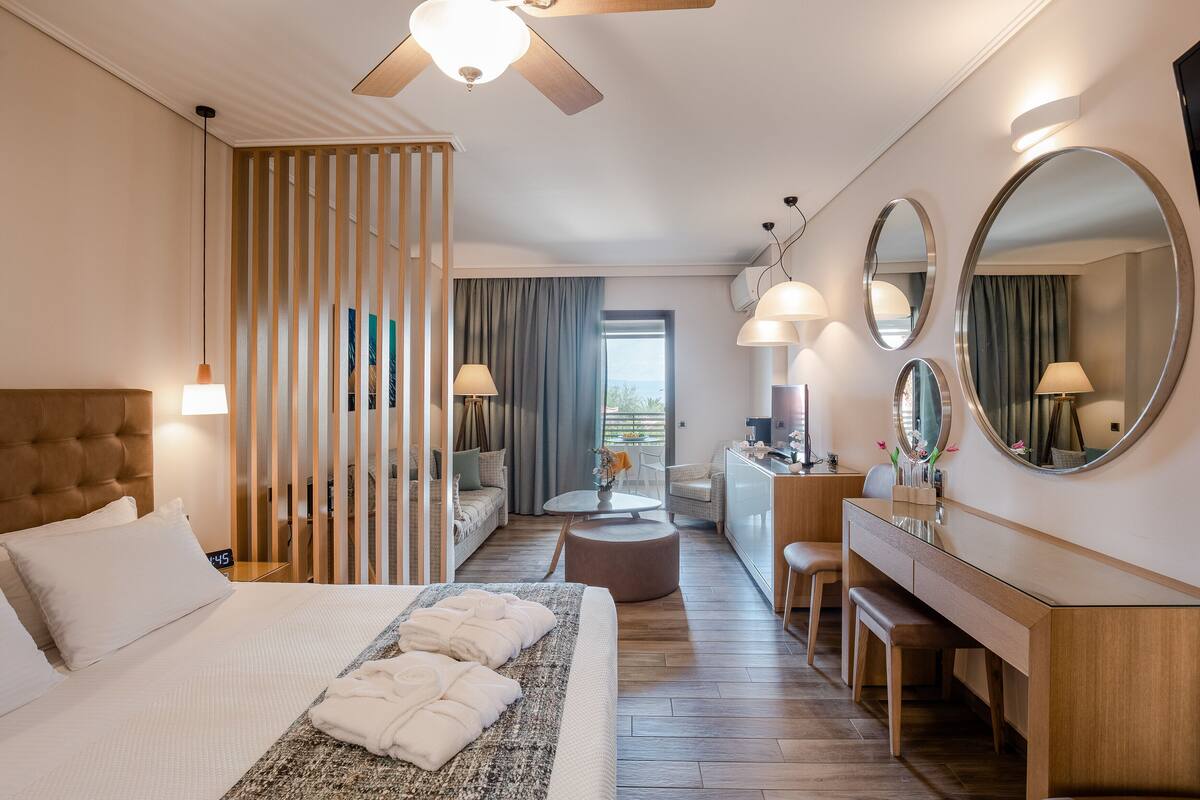 Et moderne hotelværelse med en stor seng, et skrivebord, en sofa og et spiseområde.