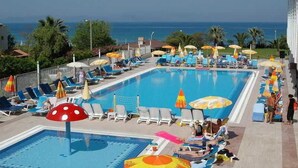 Ein Poolbereich mit Liegestühlen und Sonnenschirmen, ein kleines Schwimmbecken und Meerblick.