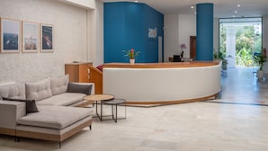 Un hall d’hôtel moderne avec un comptoir d’accueil, un canapé, une table basse et des tableaux encadrés accrochés au mur.