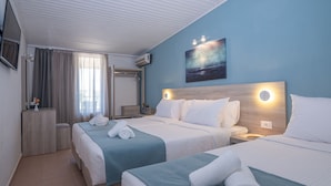 Une chambre d’hôtel avec deux lits, un téléviseur à écran plat, un tableau et une table de chevet avec une lampe.