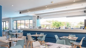 Un restaurant moderne doté de nombreuses tables et chaises, de grandes fenêtres et offrant une vue sur l’extérieur.