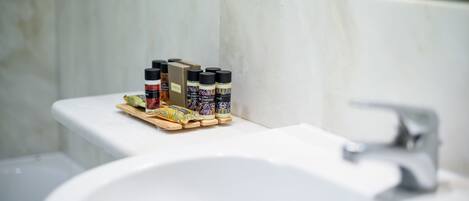 Un baño con un lavamanos blanco, un espejo y una repisa con diversos artículos de aseo.