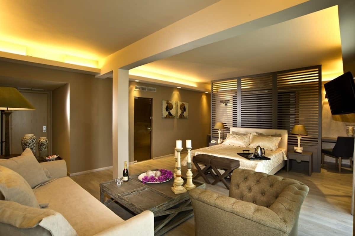 A modern hotel room with a bed, a sofa, a coffee table, and a TV.