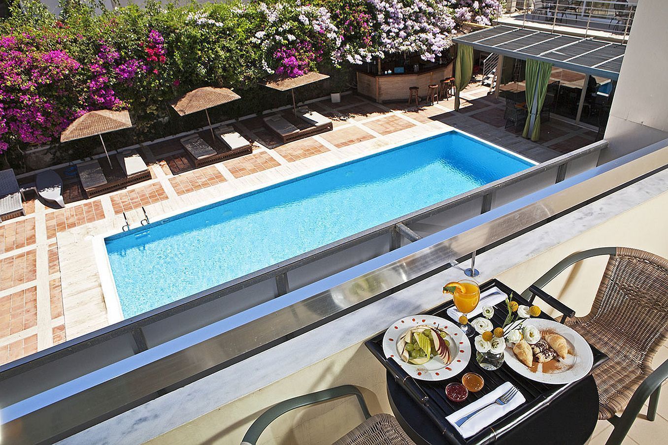 A poolside dining area with a view of a swimming pool, outdoor seating, and a bar area.