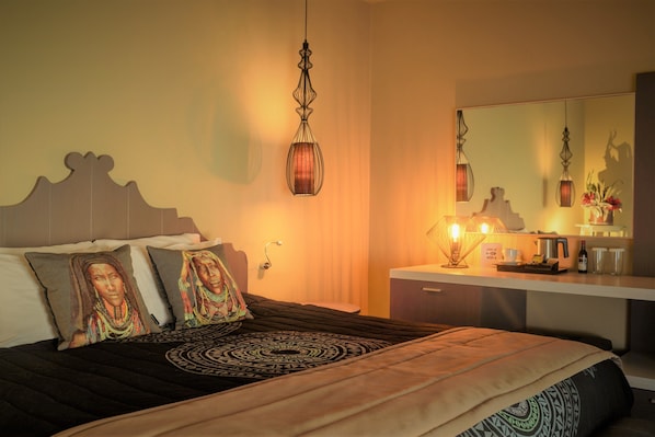 Una habitación de hotel con cama, mesita de noche, espejo y lámpara colgante.