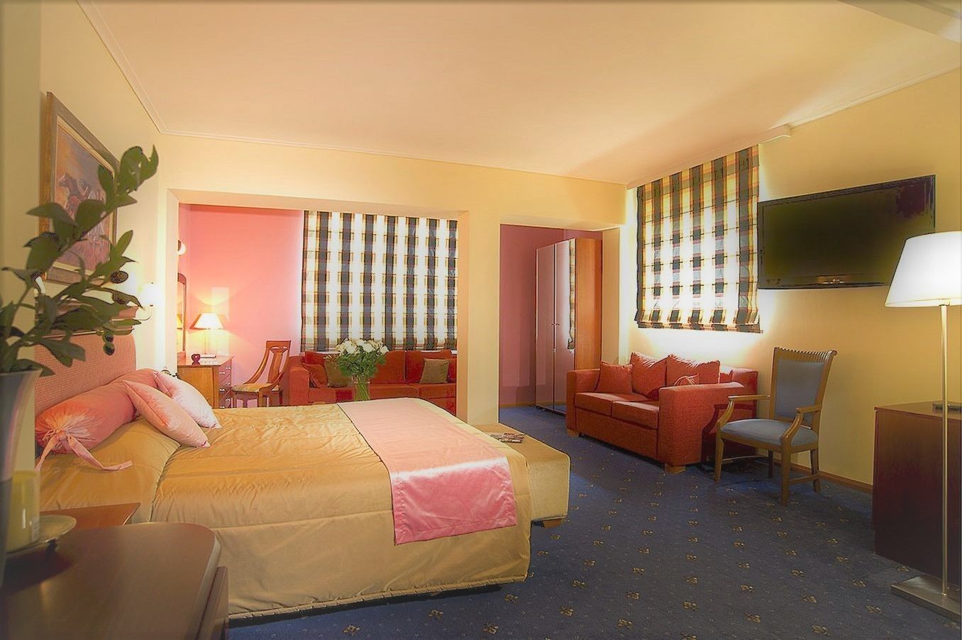 A hotel room with a bed, a sofa, a TV, and a desk.