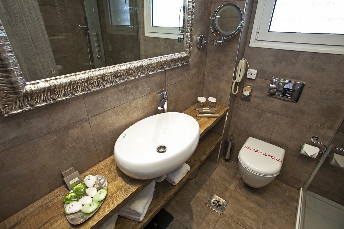 Un baño moderno con un espejo grande, un lavamanos blanco, inodoro y zona de ducha.