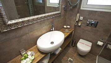 Un baño moderno con un espejo grande, un lavamanos blanco, inodoro y zona de ducha.