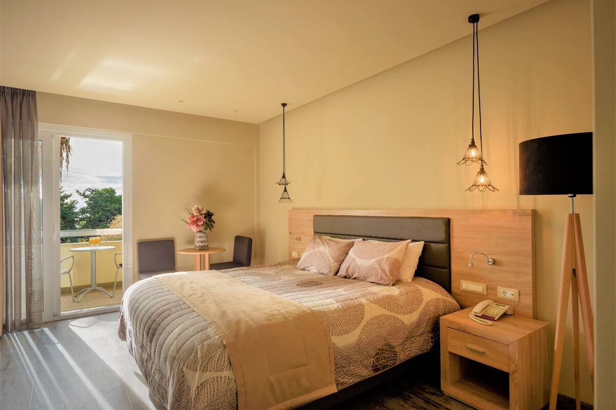 A hotel room with a large bed, bedside tables, a desk, and a view of the outdoors.