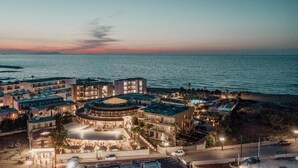 Un hotel frente al mar con varias edificaciones, una zona de piscina y vistas al océano.