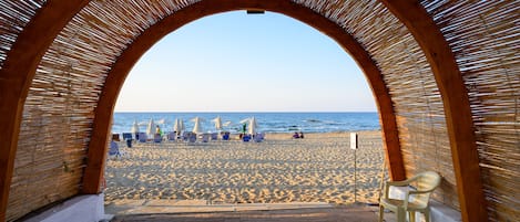 Een privéstrand, ligstoelen aan het strand, parasols, strandlakens