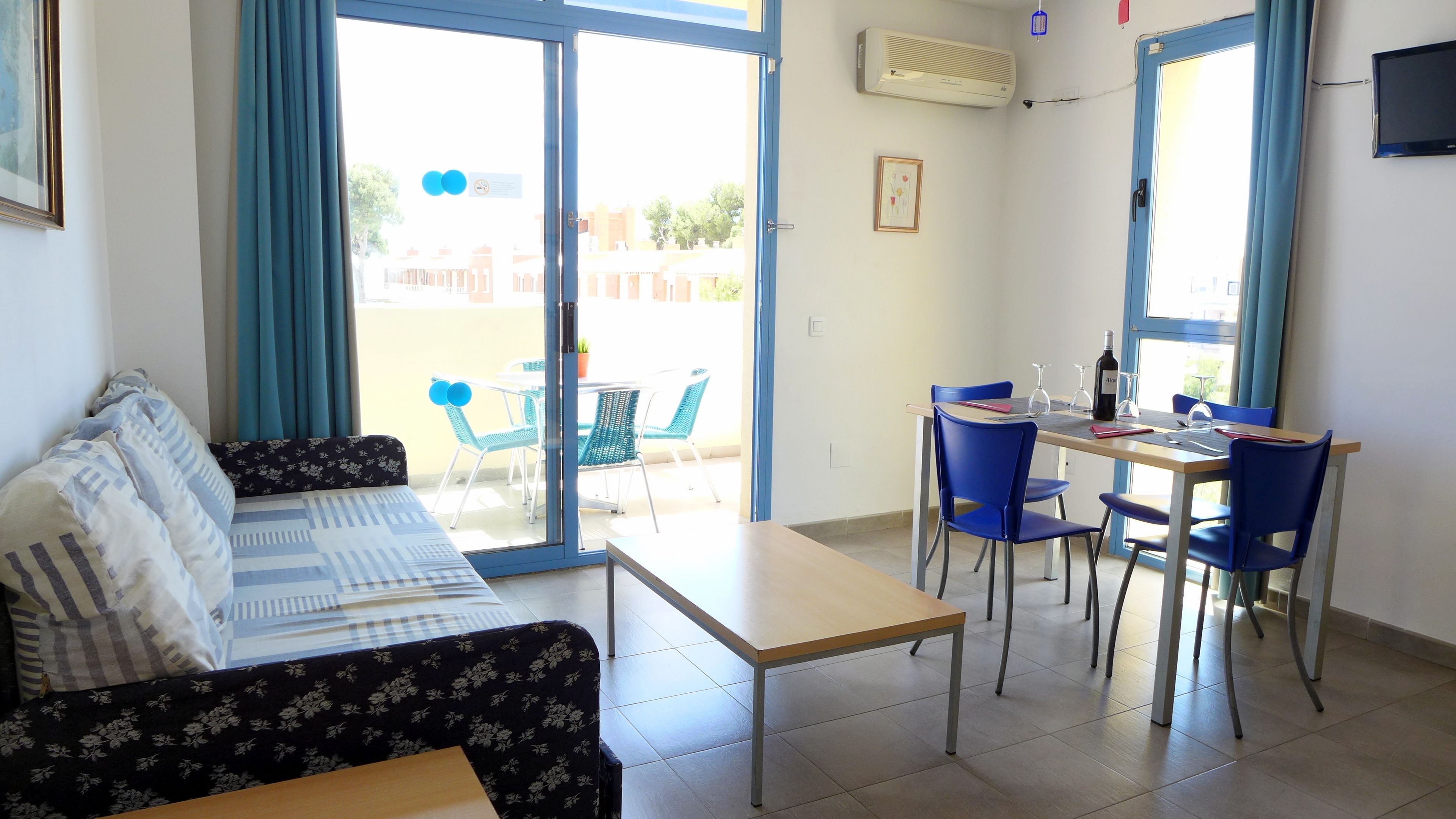 Una habitación con sofá, una mesa de comedor con sillas y vistas al exterior.