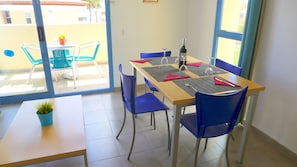 A dining area with a table set for four, blue chairs, and a potted plant on the table.
