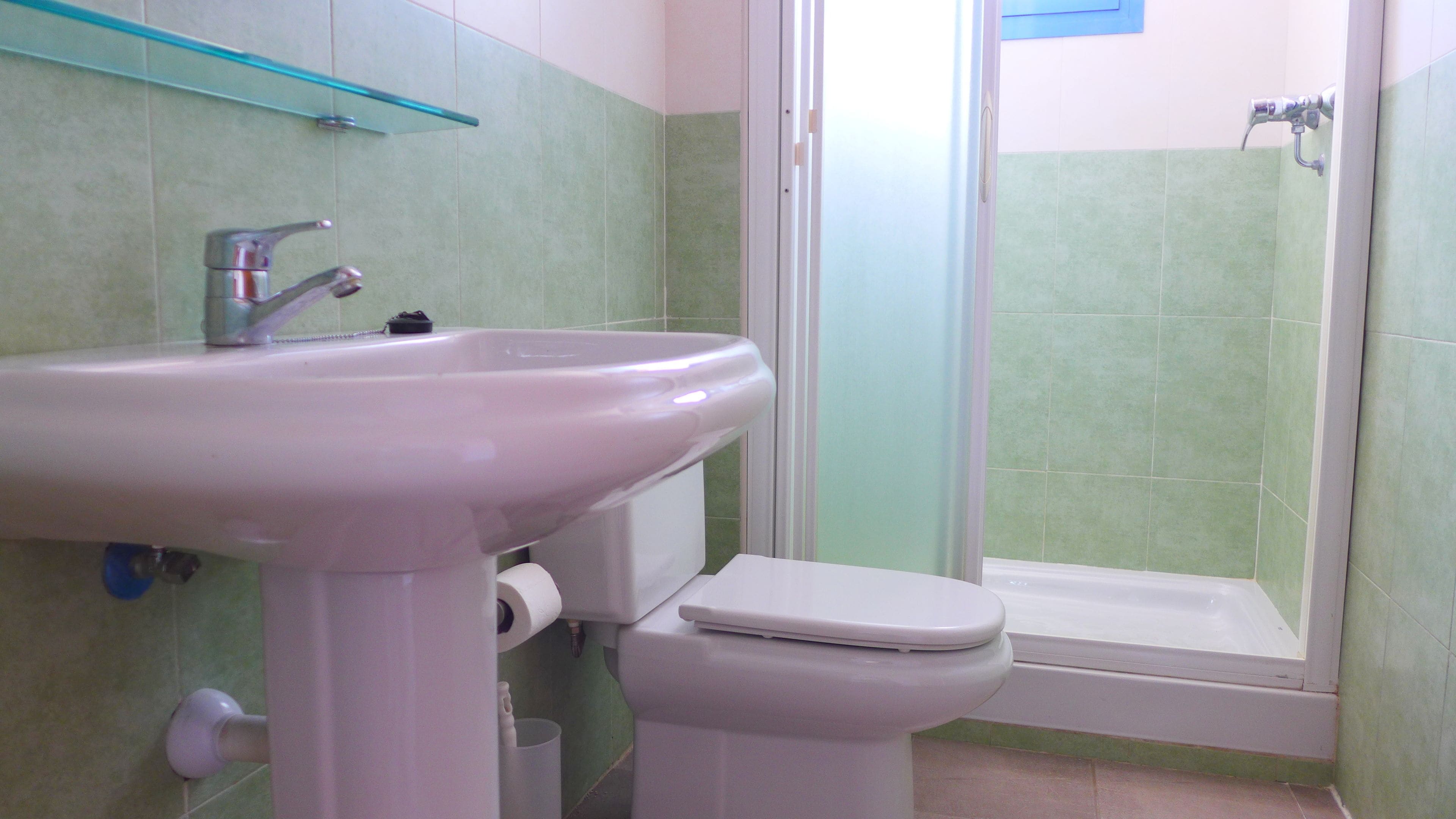 A bathroom with a white sink, toilet, and shower.