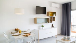 A modern, well-lit room with a dining table set for breakfast, a flat-screen TV mounted on the wall, and a small side table with cups. - RVApartaments Estartit Confort (Torroella de Montgrí)