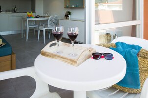 A dining area with a table set for two, featuring two wine glasses and a pair of sunglasses.
