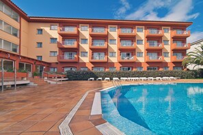A hotel with a swimming pool, multiple balconies, and a tiled patio area. - RVApartaments Estartit Confort (Torroella de Montgrí)