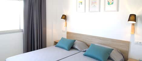 A double bed with two pillows, a wooden headboard, and two bedside lamps.