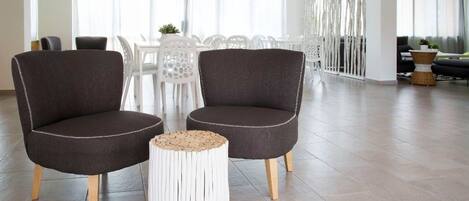Een moderne woonkamer met twee donkere fauteuils, een ronde salontafel en een witte bijzettafel.