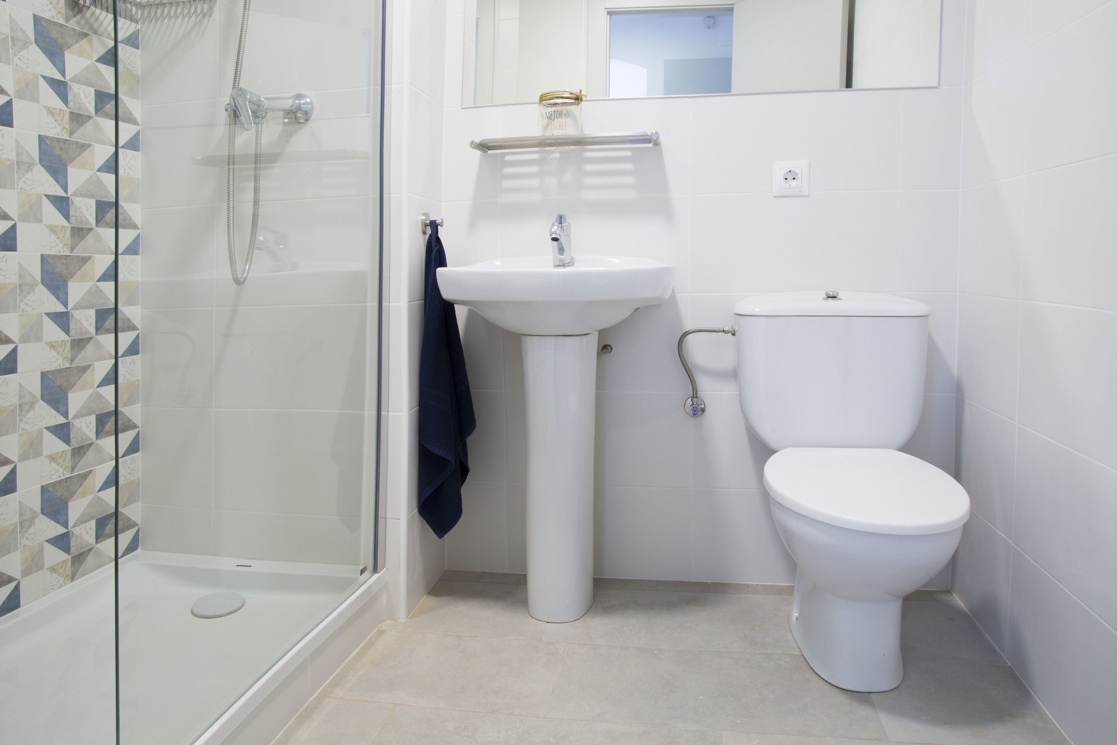A bathroom with a glass shower enclosure, a pedestal sink, and a toilet.