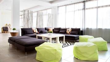 A modern living room with a sectional sofa, a coffee table, and green poufs.