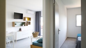 A modern, well-lit room with a white desk, a television mounted on the wall, and a window providing natural light. - RVApartaments Estartit Confort (Torroella de Montgrí)