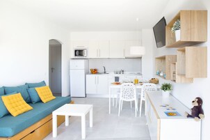 A modern apartment with a living area, kitchenette, and dining space.