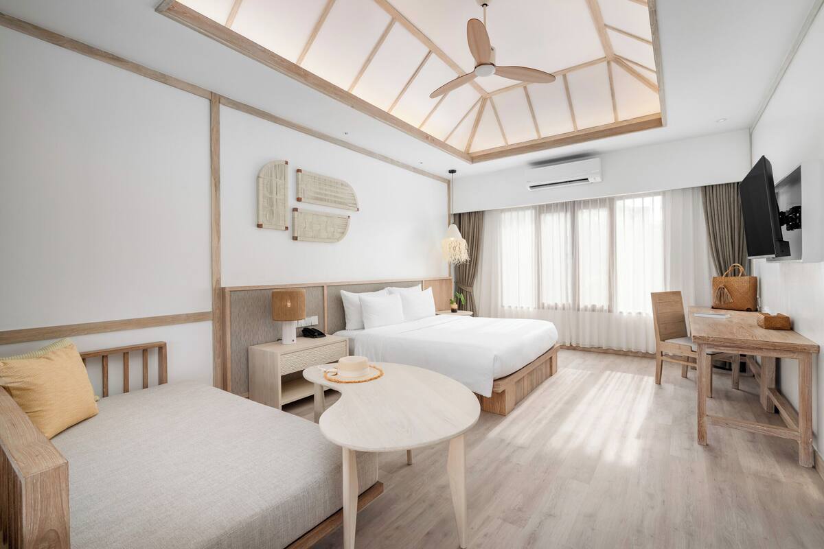 Une chambre d’hôtel moderne avec un grand lit, un canapé, une table à manger et un ventilateur de plafond.
