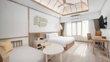 A modern hotel room with a large bed, a sofa, a dining table, and a ceiling fan.