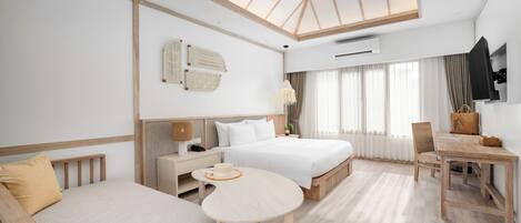 A modern hotel room with a large bed, a sofa, a dining table, and a ceiling fan.