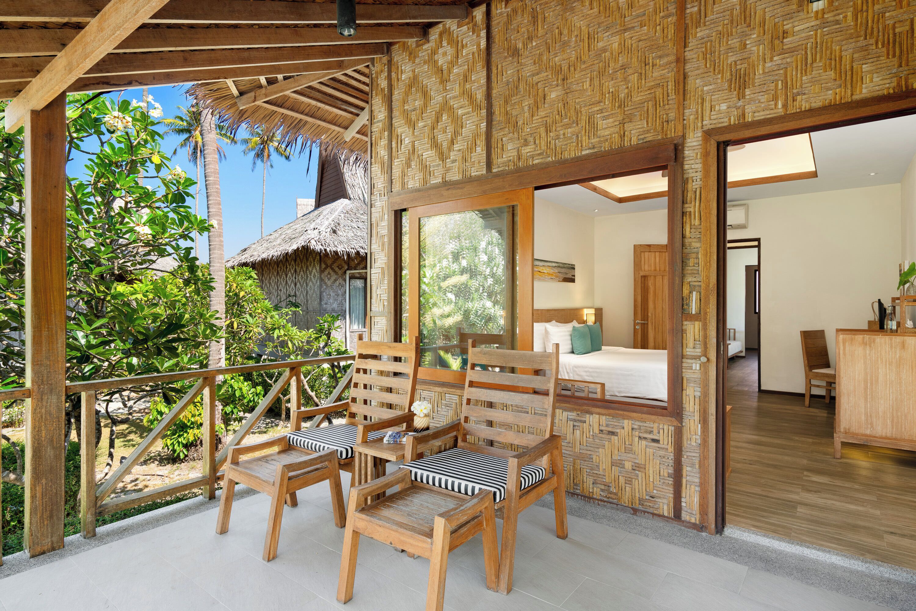 A wooden deck with chairs and a thatched-roof structure.