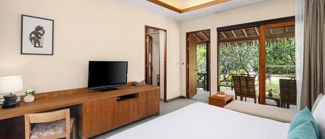 A hotel room with a bed, a wooden desk with a television, a chair, and a view of the outdoors through large windows.