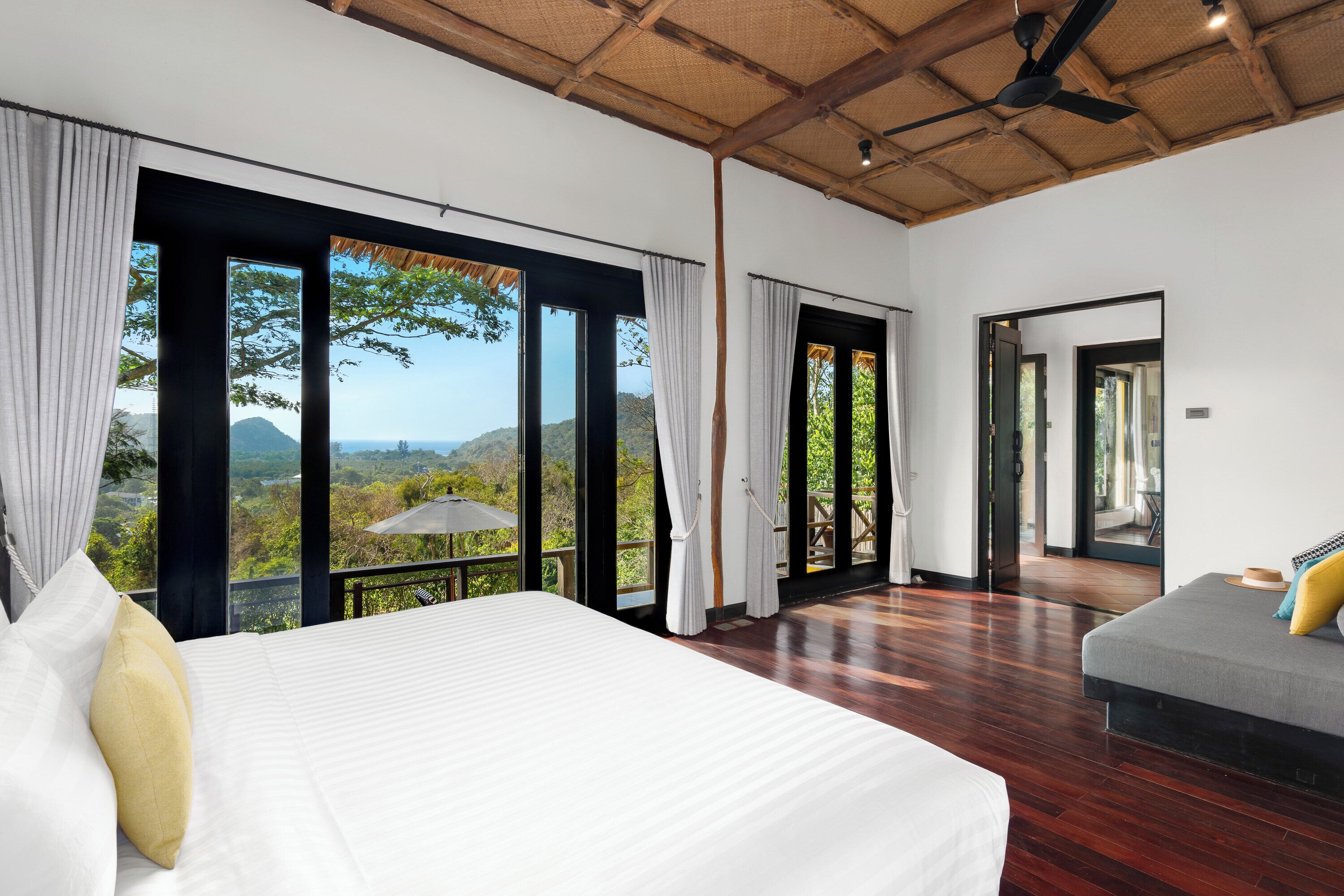 Ruime slaapkamer met een groot bed, een balkon met uitzicht op het landschap en een afzonderlijke zithoek.