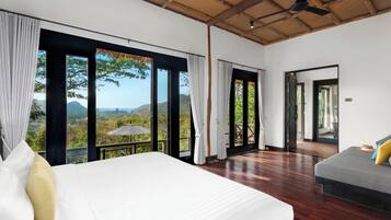 Ruime slaapkamer met een groot bed, een balkon met uitzicht op het landschap en een afzonderlijke zithoek.