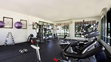 Una palestra con attrezzature per esercizi, manubri e grafici di fitness incorniciati alle pareti.