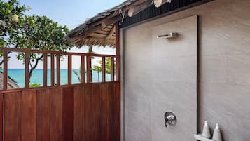 A modern bathroom with a shower, a wooden fence, and a view of the ocean.
