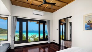 Un dormitorio con un ventanal que ofrece vistas al océano y a la playa.