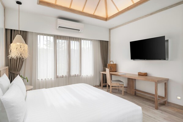 A modern hotel room with a large bed, a desk, a chair, a television, and a hanging light fixture.