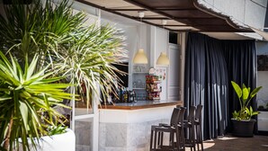 Een bar met een toog, stoelen en potplanten.