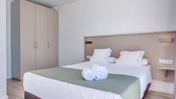 A hotel room with a bed, a wardrobe, and a bedside table.