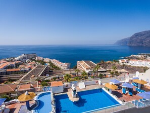 Un complexe hôtelier doté d’une piscine, offrant une vue sur la plage et comprenant plusieurs bâtiments.