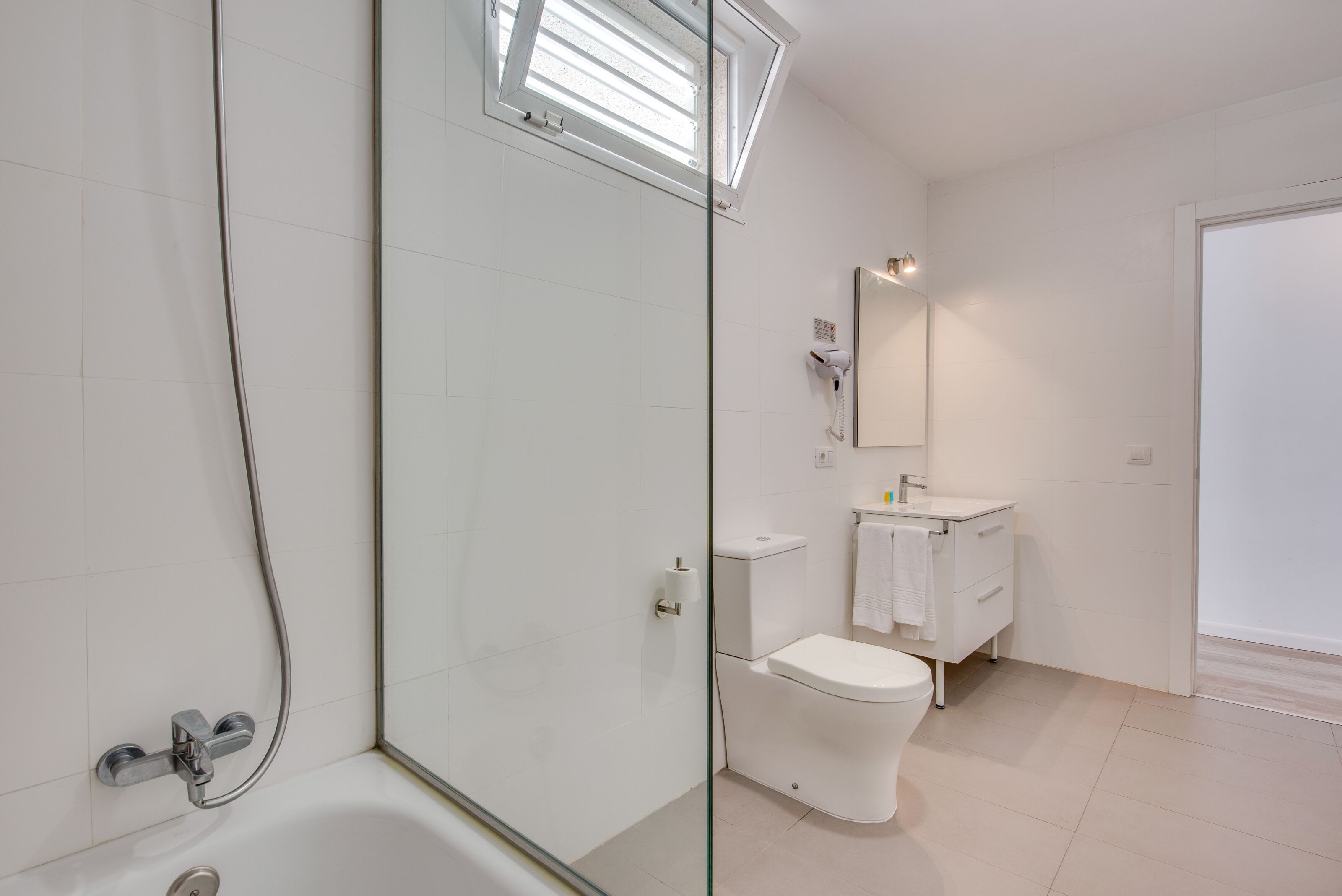 A modern bathroom with a glass shower enclosure, a white toilet, and a vanity with a mirror.
