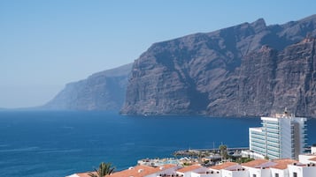 Un pueblo costero con edificios blancos, un acantilado destacado y un mar azul cristalino.