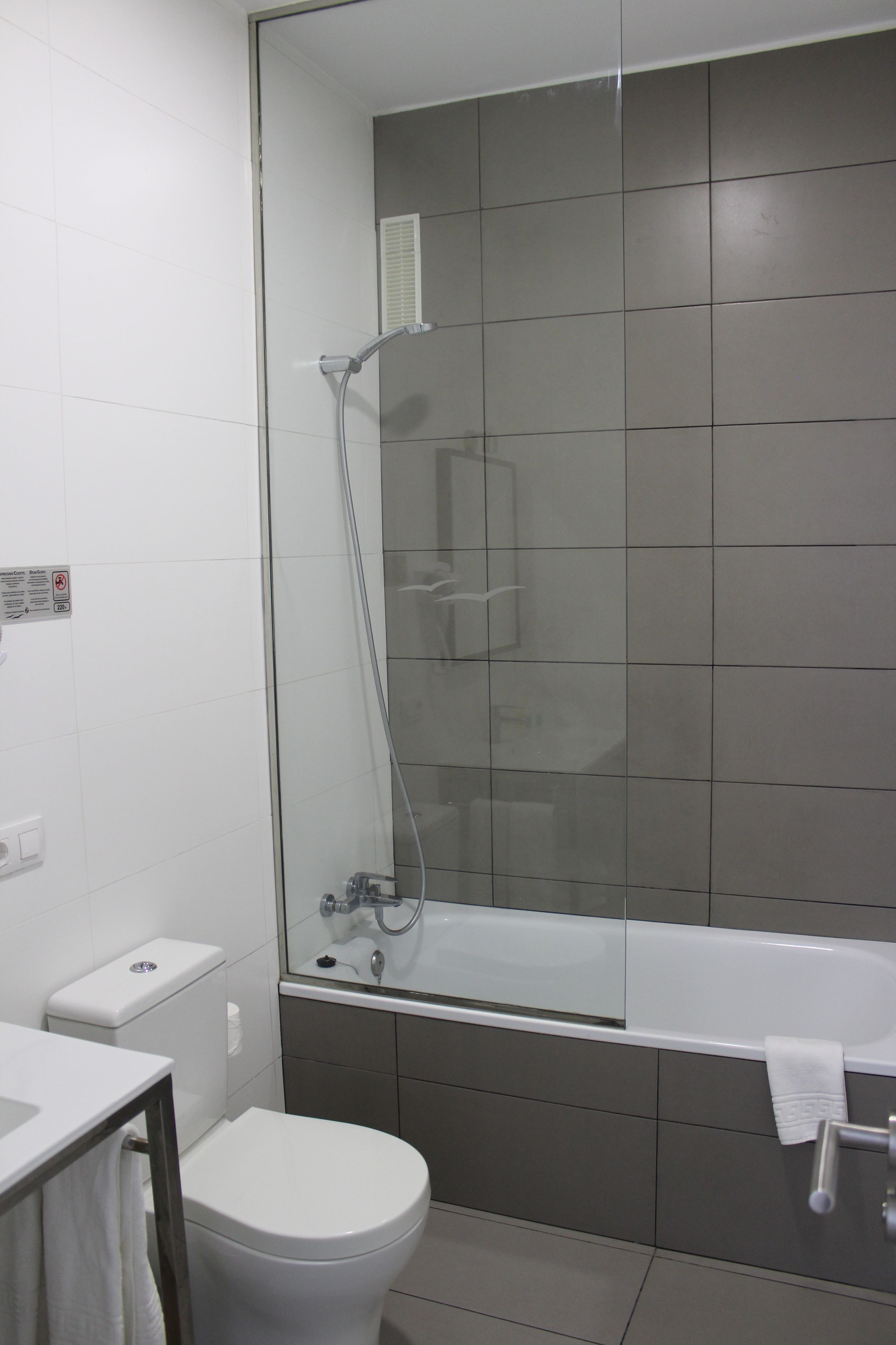 A modern bathroom with a glass shower enclosure, a white toilet, and a bathtub.