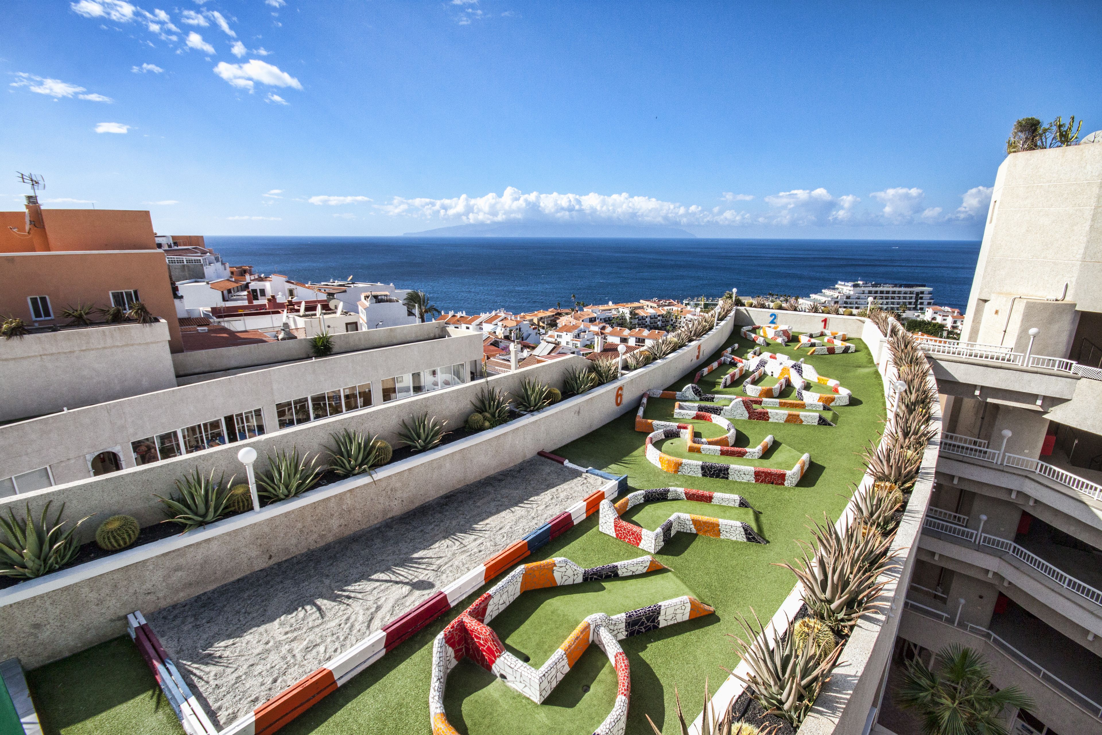 A courtyard with a pool, a view of the sea, and a building with balconies.