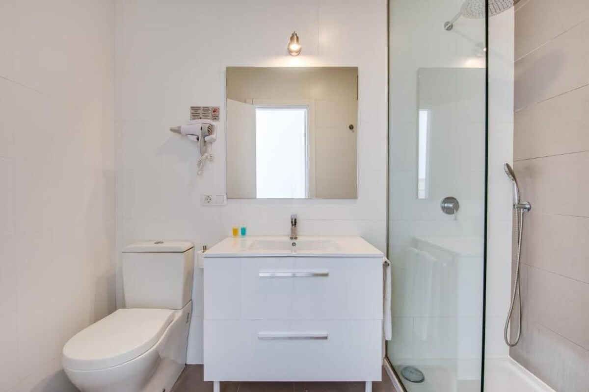Een moderne badkamer met toilet, wastafel met spiegel en douchecabine.