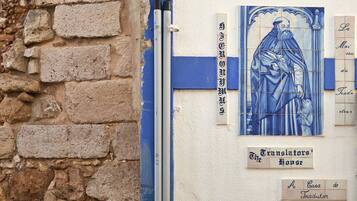 Un mur de pierre orné d’une mosaïque aux carreaux bleus et blancs représentant une figure et un texte dans une langue étrangère.