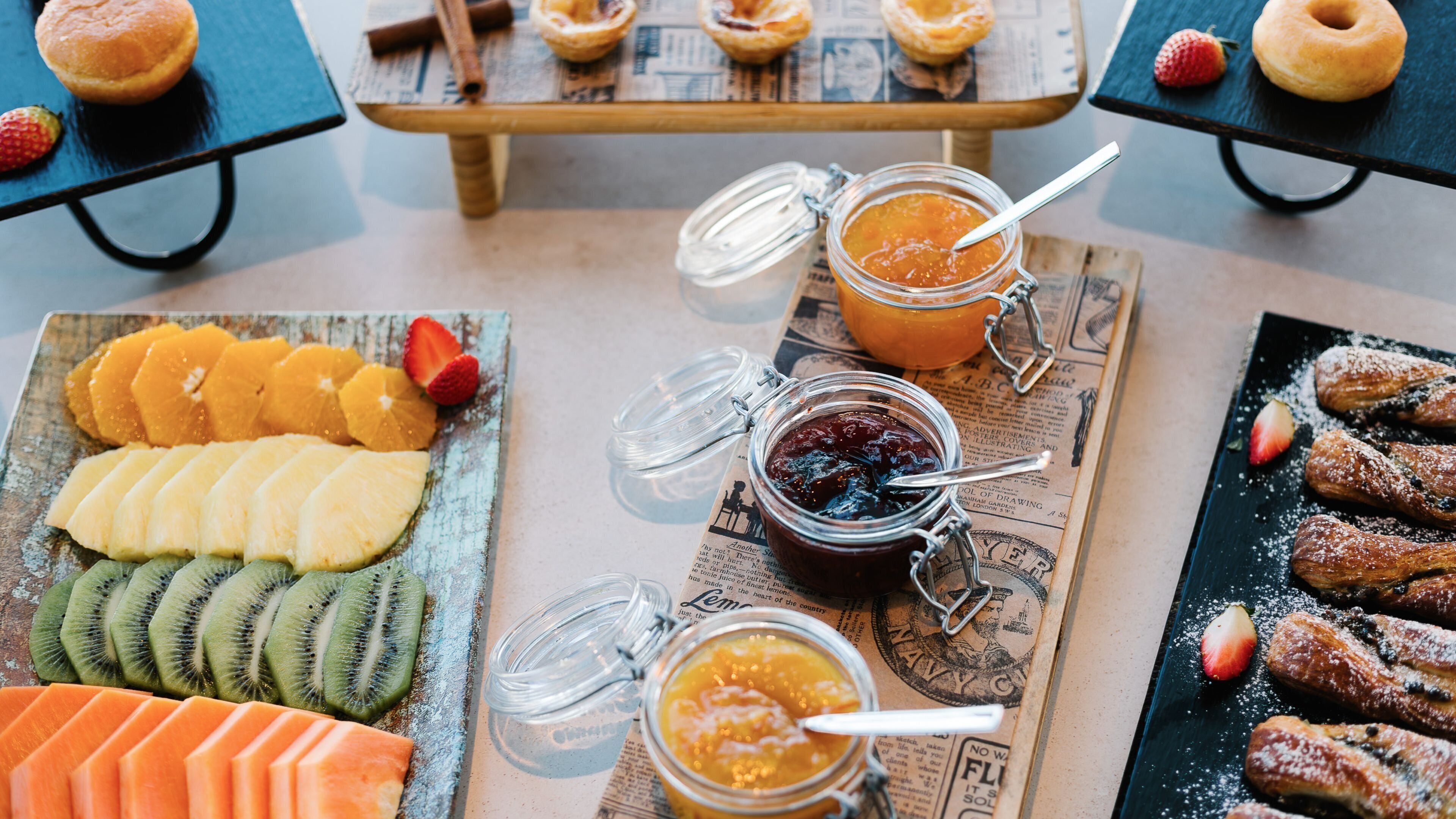 A breakfast buffet with various fruits, pastries, and jams.