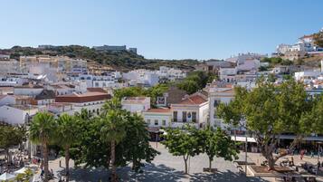 A town square with buildings, palm trees, and people.