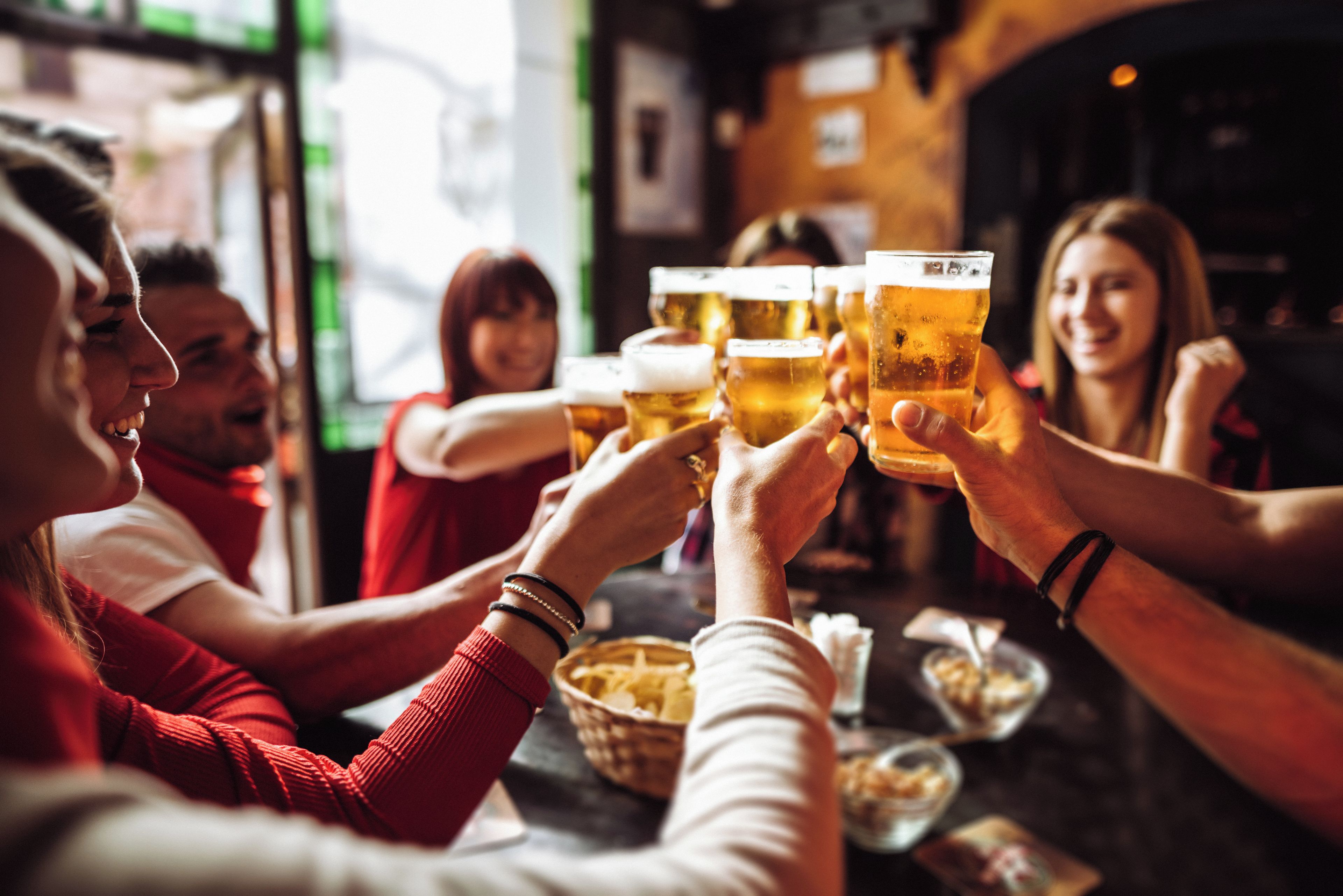 Un gruppo di persone brinda con bicchieri di birra in un bar.